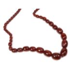A red amber type necklace, length 74cm. Gross weight 89.5 grams.