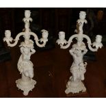 A pair of Continental white glazed porcelain figural three branch candelabra (a.f)
