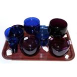 A tray of early to mid 19th century blue and amethyst glass, mostly rinsers