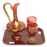 A 19th century Bohemian three piece gilt highlighted cranberry glass wine set comprising a ewer