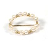 A cultured pearl hoop brooch, with applied plaque stamped '750', length 2.5cm. Gross weight 3.23