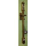 A reproduction brass ships barometer suspended on a wall gimbal bracket The brass surfaces with