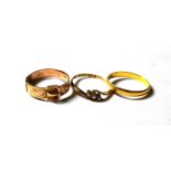 A 22 carat gold band ring, out of shape; a three stone twist ring, stamped '18CT', finger size O1/2;