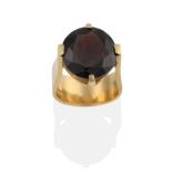 A Contemporary 18 Carat Gold Garnet Solitaire Ring, the round brilliant cut garnet in an extended