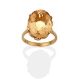 A Citrine Solitaire Ring, the oval cut citrine in a yellow claw setting to a tapered shoulder