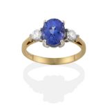 An 18 Carat Gold Tanzanite and Diamond Three Stone Ring, the oval cut tanzanite flanked by round