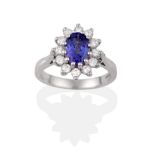 An 18 Carat White Gold Tanzanite and Diamond Cluster Ring, the oval cut tanzanite within a border of