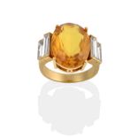 A Citrine and Diamond Ring, the oval cut citrine flanked by two graduated baguette cut diamonds on
