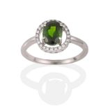 A Green Garnet and Diamond Cluster Ring, the oval cut green garnet within a halo of round