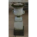 A weathered composition garden urn of campana form, on a stepped square plinth base