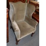 A George III style wing back armchair on ball and claw feet