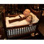 Late 19th century child's crib containing two Armand Marsille and a Nora Wellings style doll