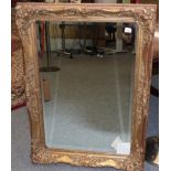 A Reproduction Gilt Mirror, with an ornate swept frame, 111cm by 80cm