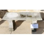 A weathered composition garden bench on scrolled supports