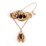 A Victorian Garnet Brooch, a garnet three stone brooch collet set in a scroll mount, with pendant