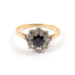An 18 Carat Gold Synthetic Sapphire and Diamond Cluster Ring, a round cut sapphire within a border
