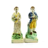 A Pair of Pearlware Figures of Gardeners, circa 1800, both holding a basket of flowers, on square