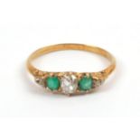 A Late 19th Century Emerald and Diamond Ring, an old cut diamond sits between two cushion cut