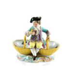 A Meissen Porcelain Figural Sweetmeat Dish, late 19th century, as an 18th century boy sitting on two