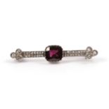 A Garnet and Diamond Brooch, the cushion cut garnet in a crimped setting centres two parallel rows
