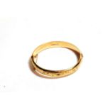 A 9 carat gold half engraved bangle, inner measurements 6cm by 5.4cm . Gross weight 13.39 grams.