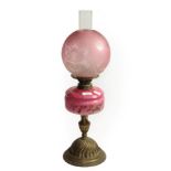 A Victorian brass oil lamp with pink and floral decorated glass reservoir