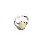 An opal ring, the oval cabochon opal in a white millegrain setting to a tapered shoulder plain