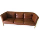 Stouby: A Beech Framed Three-Seater Sofa, upholstered in brown leather, with eight removable