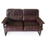 A Danish Design Stained Beech Two-Seater Sofa, covered in red/brown leather with buttoned back