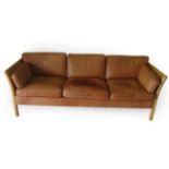 Stouby: A Danish Design Beech Framed Three-Seater Sofa, covered in tan leather, with eight removable