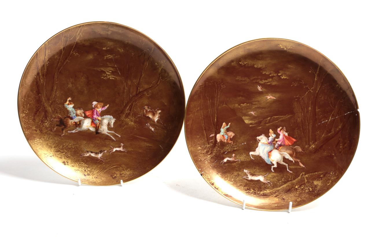 A pair of 19th century Limoges plates painted with hunting figures on horseback on a monochrome gilt