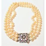 A three row cultured pearl choker, with ruby set square snap stamped '9CT', length 35cm. Gross