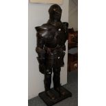 A reproduction suit of armour, holding a sword, on an ebonised plinth, 177cm high overall
