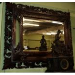 An impressive carved oak cushion framed sectional mirror, decorated with leaf scrolls