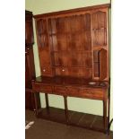 A George III oak dresser and rack, the upper section with shelves recesses and covered doors above a