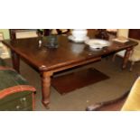 A late Victorian oak extending dining table, with four additional leaves, on turned and reeded legs,