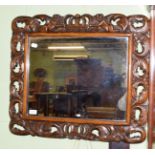 A William & Mary style carved oak mirror, foliate scroll frame with twin cherubs and crown, 63cm