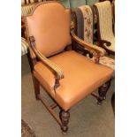 An early 20th century carved oak armchair covered in leather