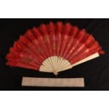 A large late 19th century bone fan with a red silk brocade leaf, the fabric woven with floral