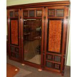 An Aesthetic movement walnut, ebonised and burr triple door mirrored wardrobe, the stepped cornice