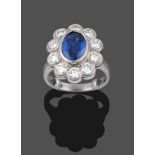 A Platinum Sapphire and Diamond Cluster Ring, the oval mixed cut sapphire in a rubbed over setting