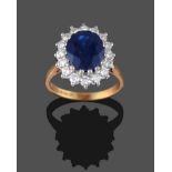An 18 Carat Gold Sapphire and Diamond Cluster Ring, the oval mixed cut sapphire within a border of