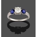 A Diamond and Sapphire Three Stone Ring, a round brilliant cut diamond between two round cut