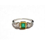 An emerald and diamond three stone ring with diamond set shoulders (shank worn), finger size N.