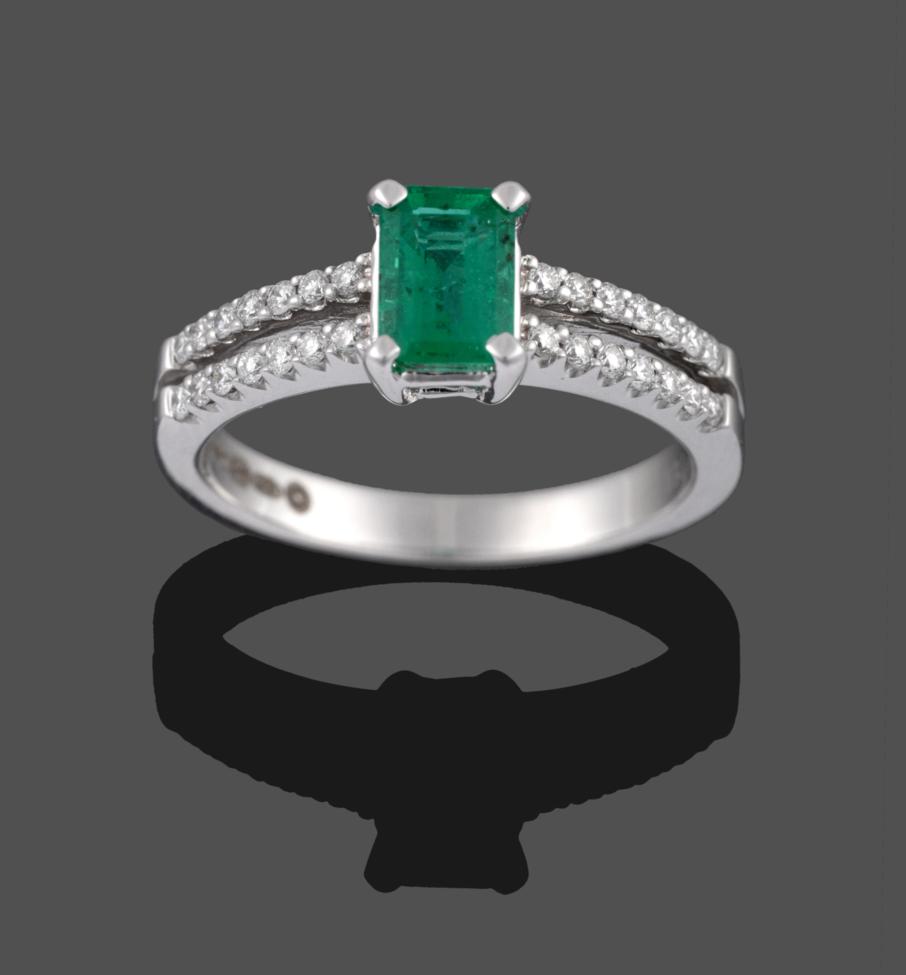 An 18 Carat White Gold Emerald and Diamond Ring, the emerald-cut emerald in a four claw setting,