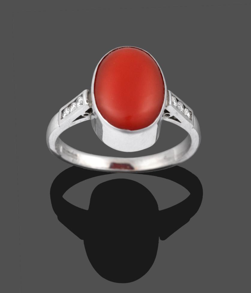 An 18 Carat White Gold Coral and Diamond Ring, the oval cabochon coral in a white collet setting
