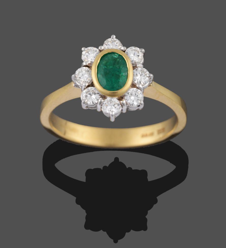 An 18 Carat Gold Emerald and Diamond Cluster Ring, the oval cut emerald in a yellow collet setting