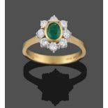 An 18 Carat Gold Emerald and Diamond Cluster Ring, the oval cut emerald in a yellow collet setting