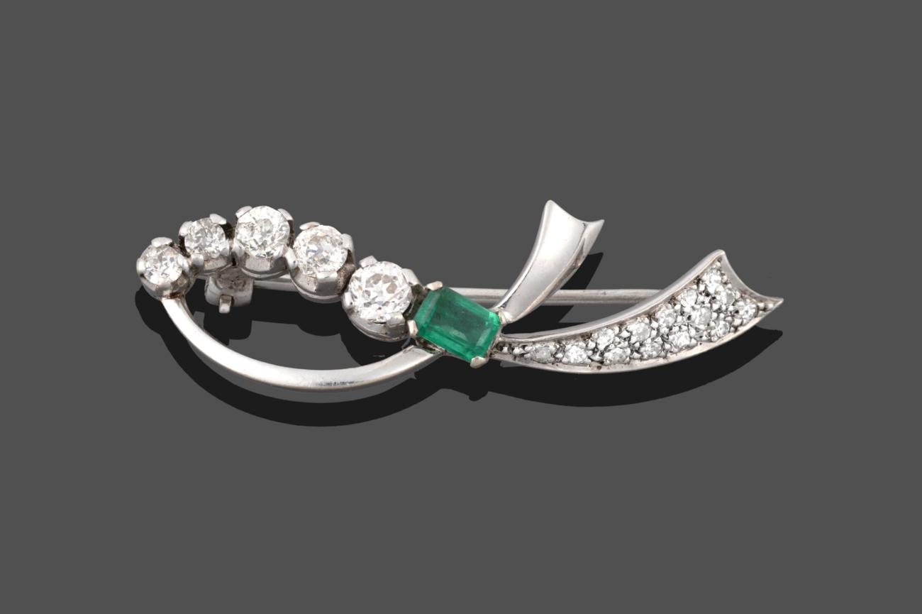 An Emerald and Diamond Brooch, realistically modelled as a white ribbon with an emerald-cut