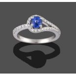 An 18 Carat White Gold Sapphire and Diamond Ring, the oval cut sapphire in a looped frame, inset